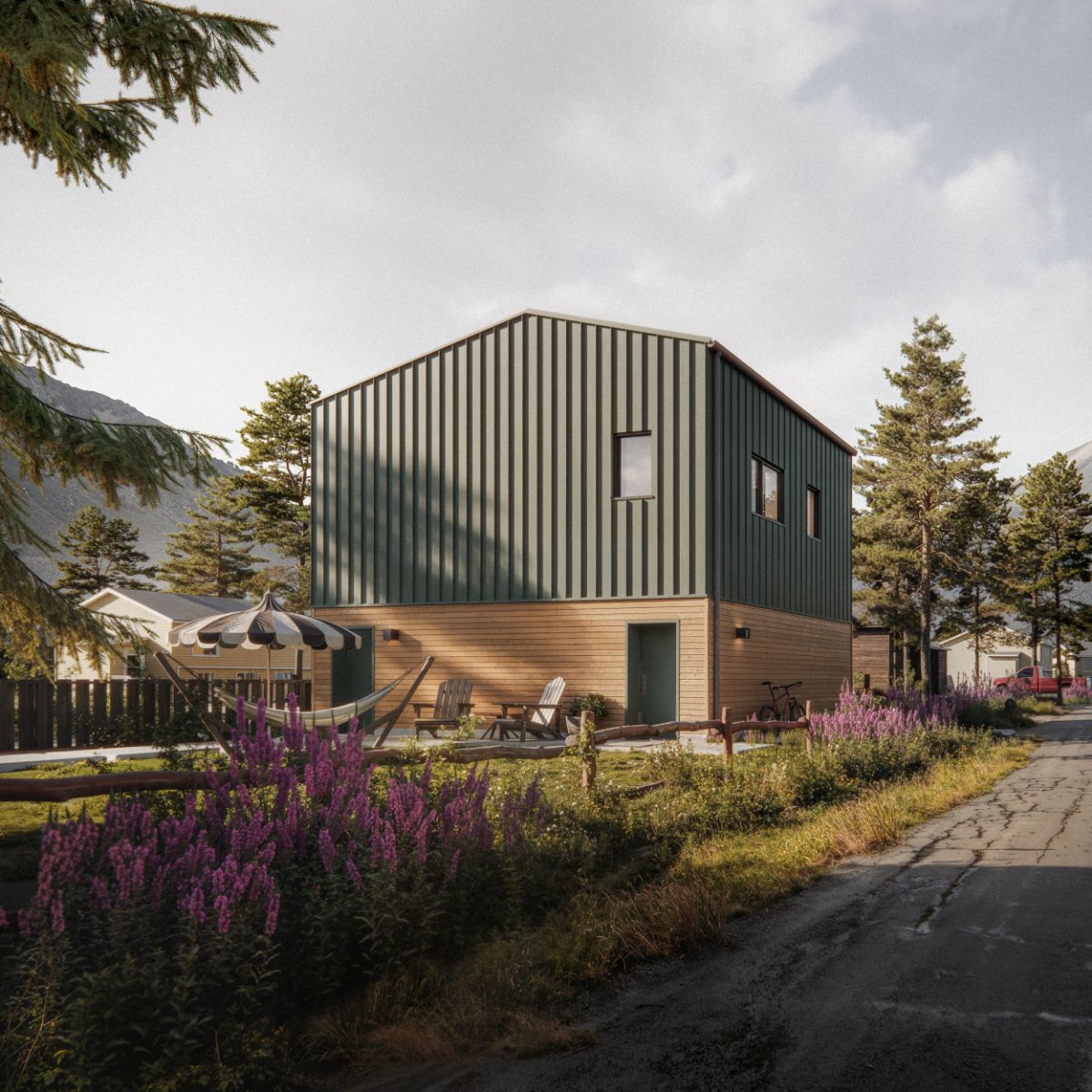 A 3D rendering of a two‑storey ADU with green metal siding on the upper level and wooden siding on the lower level. A small patio with wooden chairs, a hammock, and a striped umbrella is visible in front of the structure. Neighboring houses, tall trees, and distant mountains appear in the background under a partly cloudy sky.